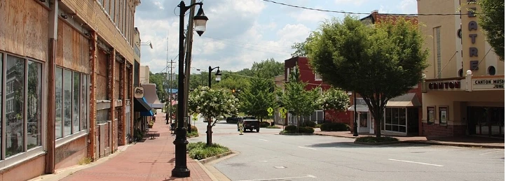 Downtown street with historic storefronts, trees, streetlights, and theater marquee.