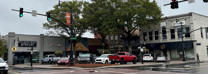Downtown Austell intersection with storefronts, parked cars, and traffic lights after rain.