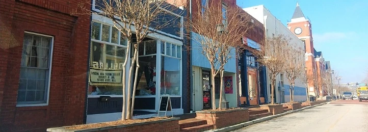 Downtown Austell street with colorful storefronts, bare trees, and clock tower.