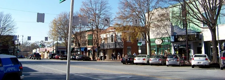 Downtown Austell street with shops, parked cars, bare trees, and storefront awnings.