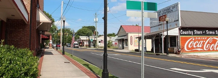Downtown Powder Springs street with sidewalk, storefronts, lampposts, and Coca-Cola mural.